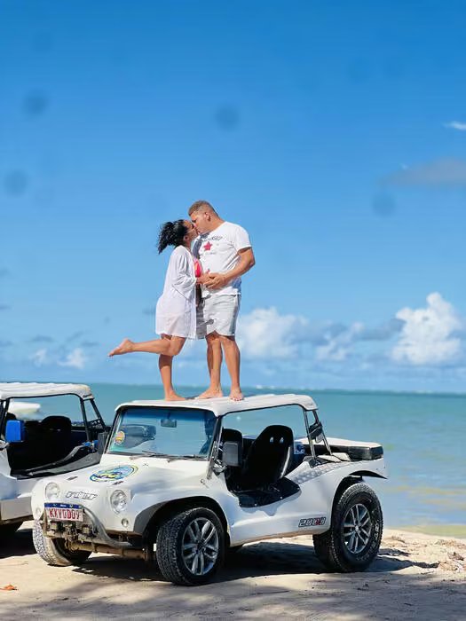 Casal em cima de um buggy na praia